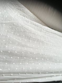 an unmade bed with white sheets and polka dots on the covers is seen in this image