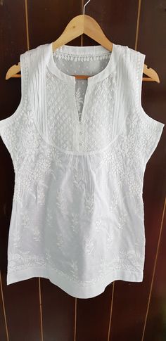 Cotton self embossed white Sleeveless yoke Tunic hand embroidered in chikankari. 3 button loops/ no side slits. Available in white/navy/coral Sizes available : XXS - bust 32 (inches) XS - bust 34 (inches) S - bust 36 (inches) M - bust 38 (inches) L - bust 40 (inches) XL - bust 42 (inches) 0X - bust 44 (inches) Lenght - 32 - 33 inches White Sleeveless Top With Intricate Embroidery, White Sleeveless Top With Resham Embroidery, Keats Quotes, Women Tops Online, Sleeveless Kurta, Kurta Top, Short Kurta, Cotton Kurti Designs, Blouse Price