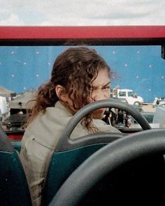 a woman sitting in the driver's seat of a bus looking out at traffic