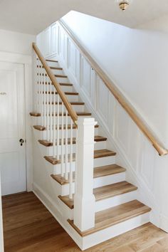 a white staircase with wooden handrails and wood flooring in a home's entryway