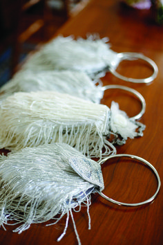 several pieces of silver metal on a wooden table with white fringes and rings attached to them