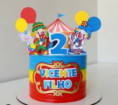 a birthday cake with two clowns on top and balloons in the shape of numbers