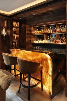 a bar with stools and bottles on the shelves