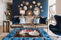 a living room filled with furniture and mirrors on the wall above it's coffee table