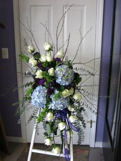 a bouquet of blue and white flowers sitting on a stepladder in front of a door