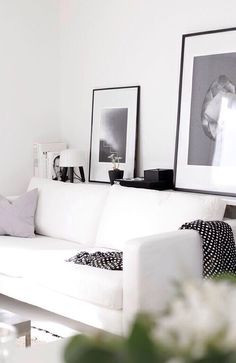 a living room with white furniture and pictures on the wall