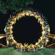 a large circular wreath with flowers and lights on it is lit up in the dark