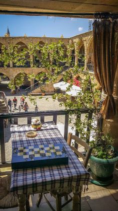 a table with a checkered cloth on it sitting in front of a window overlooking an outdoor courtyard