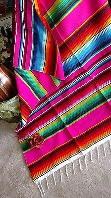 a colorful blanket is laying on the floor next to a vase and some other items