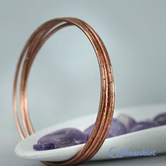 "This set of 4 handmade copper bangle bracelets absolutely sing while you are wearing them! Made from 12 gauge copper wire that has been soldered, then textured, they are light and comfortable, and can be custom made to order in whatever size you would prefer. They can also be sealed, to help keep the copper from reacting with your skin and to help keep the copper bright and shiny, or antiqued to give the copper a darker finish. Just let me know your preference on checkout. Bangle Sizes: (Rememb Gold Electroformed Bracelets For Gift, Handmade Copper Bangle, Rose Gold Copper Bangle As Gift, Copper Bangle Gift, Bohemian Rose Gold Bangle For Gift, Rose Gold Bohemian Bangle As Gift, Bohemian Rose Gold Bangle Gift, Copper Bangles, Handmade Bangle Bracelets