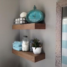 two wooden shelves with towels and a clock on the wall above them in a bathroom