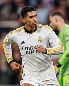 a soccer player running with the ball in his hand and another man behind him looking on