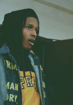 a young man with dreadlocks wearing a yellow and black shirt is looking at the camera