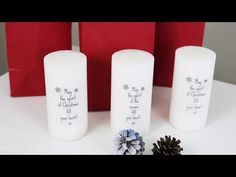 three white candles sitting on top of a table next to some pine cones and flowers