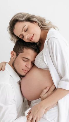 a pregnant man and woman embracing each other while they are holding their stomachs together