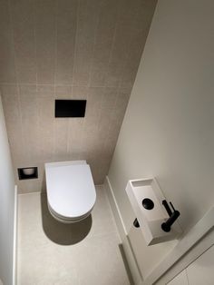 a white toilet sitting in a bathroom next to a wall mounted faucet and sink