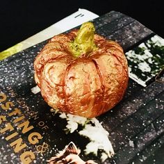 there is a pumpkin on top of a book with other items around it and an orange peel in the middle