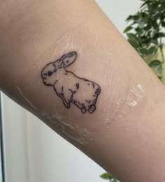 a person with a tattoo on their arm that has a small rabbit drawn on it