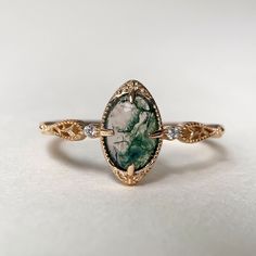 a close up of a ring on a white surface with a green stone in the middle