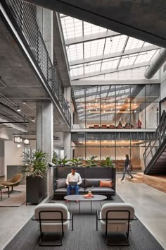 a man sitting on a couch in the middle of a room with lots of windows