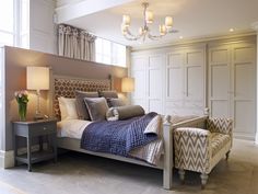 a bedroom with a bed, two chairs and a chandelier