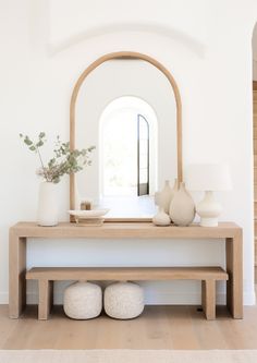 a table with two vases and a mirror on it