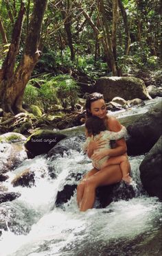 two women are sitting on rocks in the water and one is holding another woman's back