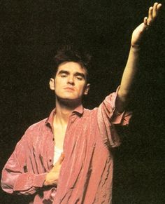 a young man is holding his hand up in the air while standing against a black background