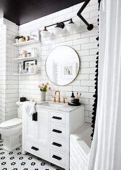 the bathroom is decorated in black and white with gold accents, including a round mirror