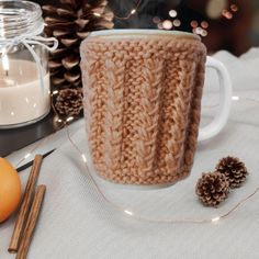 a knitted mug cozys up next to some cinnamon sticks