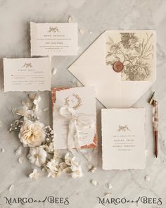 the wedding stationery is laid out on top of the marble table with flowers and an envelope