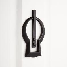 a black door handle on the side of a white door with an open circle design