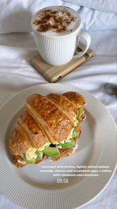 a white plate topped with a cut in half sandwich next to a cup of coffee