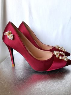 a pair of red high heeled shoes with pearls on the toe and heels are sitting on a table