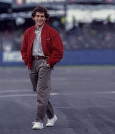 a man standing on top of a tennis court wearing a red jacket and khaki pants