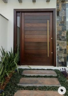 a modern wooden door with stone steps leading up to the front entrance and side entry