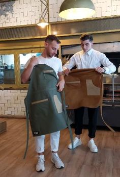 two men in aprons are holding up some kind of bag