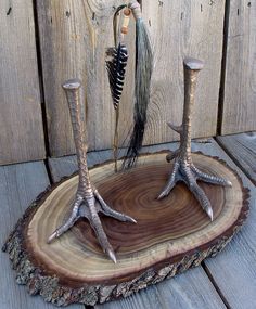 two deer antlers are standing on a piece of wood with feathers attached to them