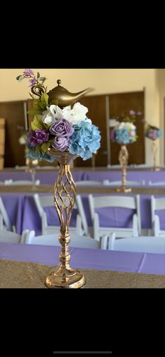 a vase filled with flowers sitting on top of a table next to rows of chairs