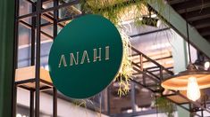 a green sign hanging from the side of a building next to lights and potted plants