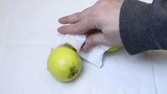 a person is peeling an apple on a white tablecloth with a cloth around it