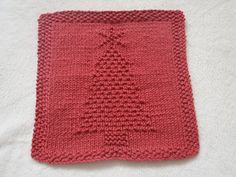 a red knitted dishcloth with a tree on it