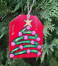 a wooden ornament hanging from a tree decorated with pink and green christmas ornaments