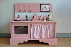 a pink toy kitchen is shown with pictures on the wall