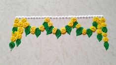 yellow and green flowers are hanging on a white string with beaded beads around it