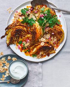 a white plate topped with food next to a bowl of yogurt