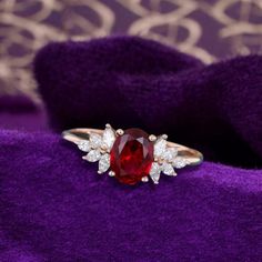 a ring with a large red stone surrounded by small white stones on purple velvet material