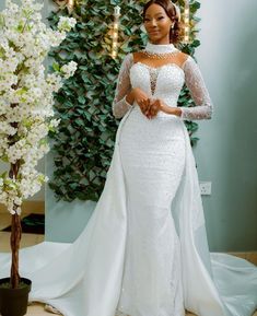 a woman in a wedding dress standing next to a flower pot with white flowers on it