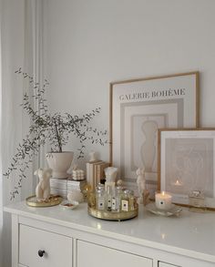 a white dresser topped with vases and candles next to a framed photograph on top of it