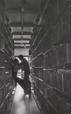 two people standing in the middle of a library with bookshelves full of books